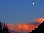 Sunset lights up the clouds over Crested Butte as a nearly full moon rises.