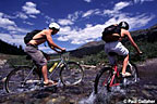 Kids mountain biking through creek